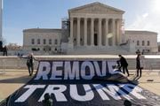 Demonstrators hold a banner outside of the U.S. Supreme Court, Thursday, Feb. 8, 2024, in Washington. The U.S. Supreme Court on Thursday will take up a historic case that could decide whether Donald Trump is ineligible for the 2024 ballot under Section 3 of the 14th Amendment. (AP Photo/Jose Luis Magana)