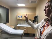 Tania Lyons, services director for Syracuse's new crisis stabilization center, points to the one-way glass in an exam room that allows staff to keep an eye on patients in mental or drug-induced crisis. The center, located on North Salina Street, is run by Helio Health.
